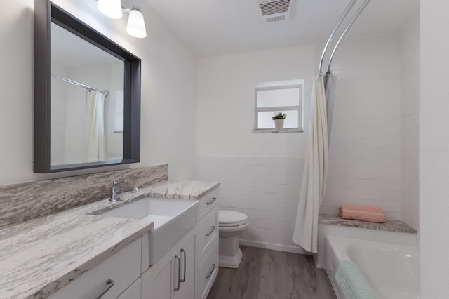 full bathroom featuring hardwood / wood-style floors, vanity, tile walls, toilet, and shower / bath combo