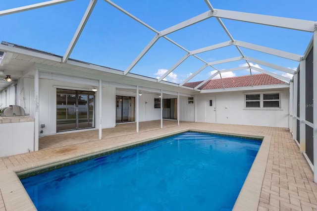 rear view of property featuring glass enclosure, an outdoor kitchen, and a patio area