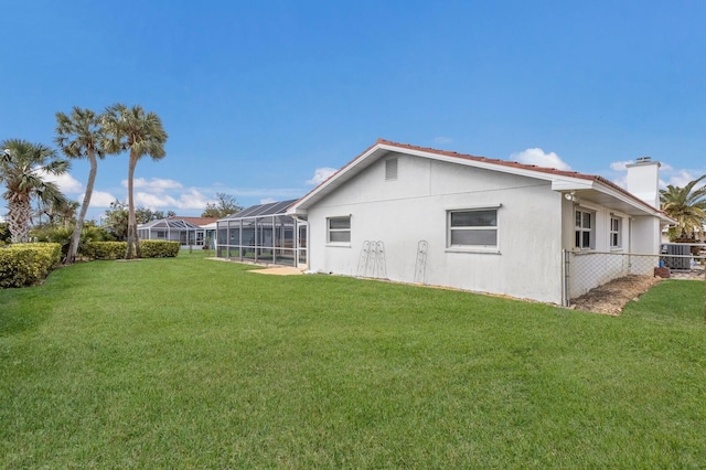 exterior space with glass enclosure, central AC, and a lawn