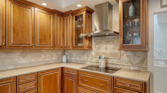 kitchen with tasteful backsplash, black electric cooktop, light stone countertops, and wall chimney range hood