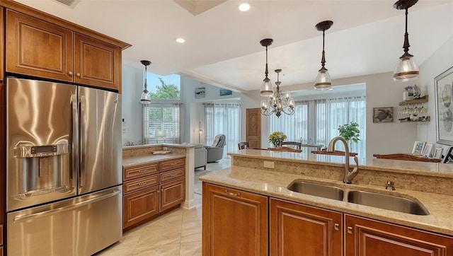 kitchen with sink, stainless steel fridge with ice dispenser, light stone counters, a notable chandelier, and decorative light fixtures