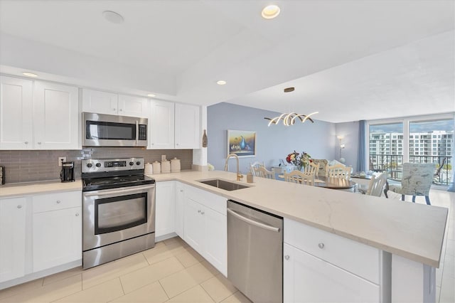 kitchen featuring kitchen peninsula, sink, white cabinets, and stainless steel appliances