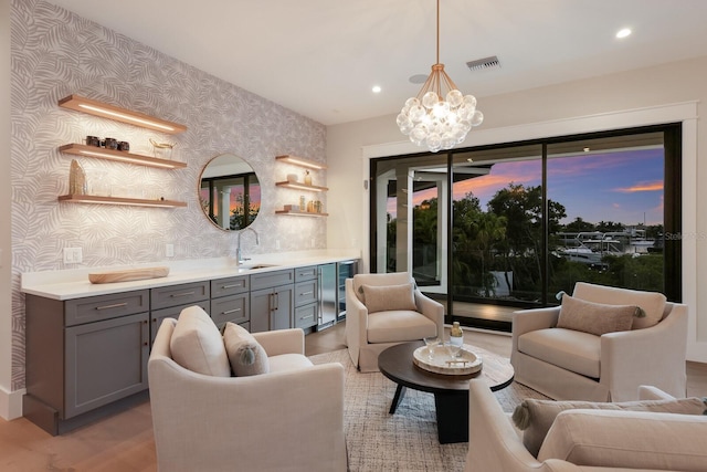 living room featuring a chandelier, light hardwood / wood-style flooring, wine cooler, and sink