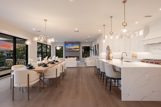 kitchen featuring decorative backsplash, dark hardwood / wood-style flooring, sink, white cabinetry, and hanging light fixtures