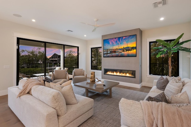 cinema room with ceiling fan, a fireplace, and light hardwood / wood-style floors