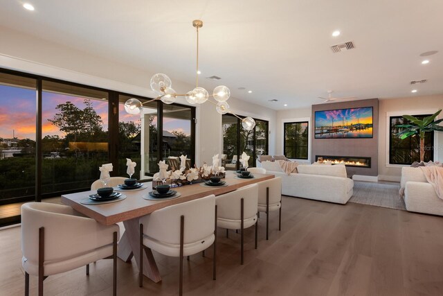 dining space featuring ceiling fan, wood-type flooring, and a fireplace