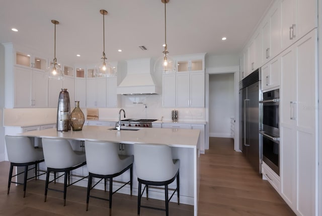 kitchen with white cabinets, custom exhaust hood, sink, and decorative light fixtures