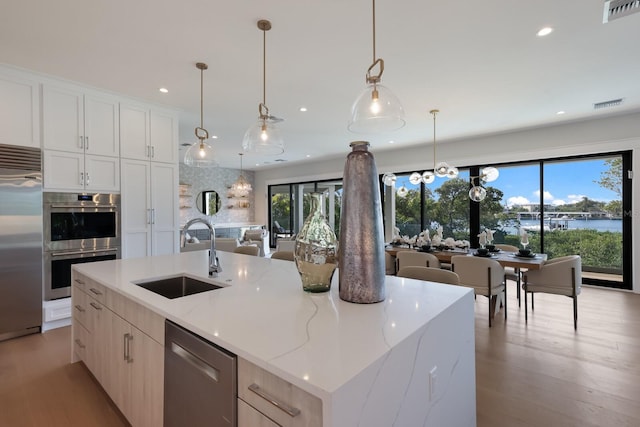 kitchen with light stone countertops, stainless steel appliances, sink, pendant lighting, and a large island