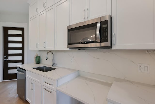 kitchen featuring light stone countertops, sink, white cabinets, and appliances with stainless steel finishes