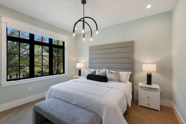 bedroom with multiple windows, light hardwood / wood-style floors, and an inviting chandelier