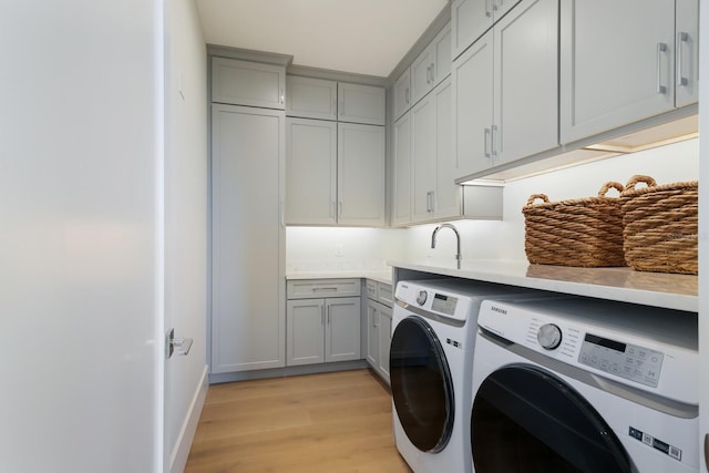 clothes washing area featuring cabinets, separate washer and dryer, and light hardwood / wood-style floors