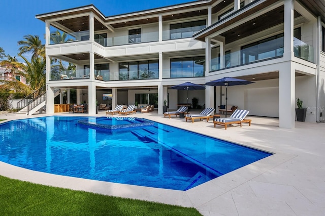 rear view of property with a patio area and a pool with hot tub