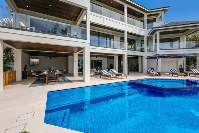 back of property with a patio area, ceiling fan, and a pool with hot tub