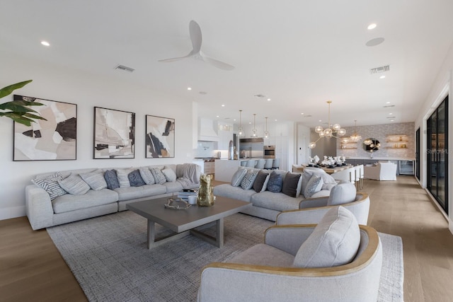 living room featuring ceiling fan with notable chandelier and hardwood / wood-style flooring