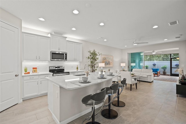 kitchen with ceiling fan, sink, an island with sink, white cabinets, and appliances with stainless steel finishes