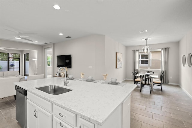 kitchen with stainless steel dishwasher, ceiling fan, sink, white cabinets, and an island with sink