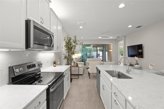 kitchen featuring white cabinetry, sink, ceiling fan, stainless steel appliances, and decorative backsplash