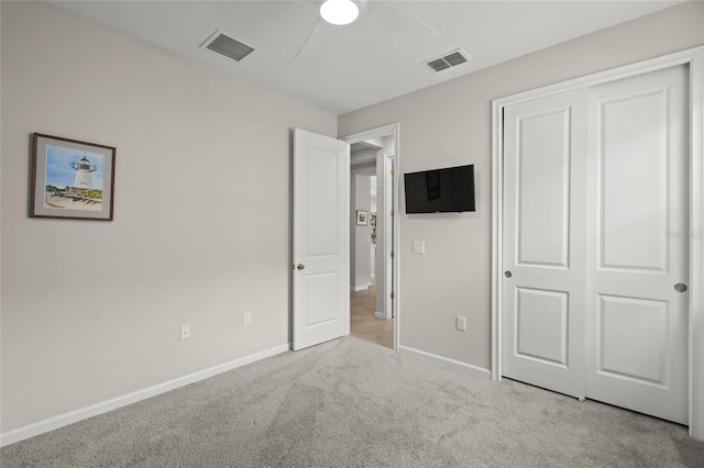 unfurnished bedroom with a closet, light colored carpet, and ceiling fan