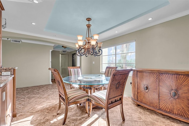 dining space featuring an inviting chandelier, ornamental molding, and a tray ceiling