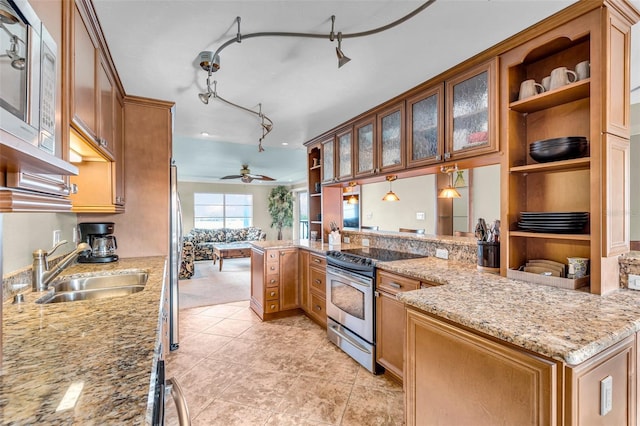 kitchen with sink, light stone counters, kitchen peninsula, pendant lighting, and stainless steel appliances