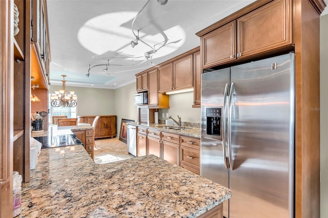 kitchen featuring light stone counters, appliances with stainless steel finishes, sink, and hanging light fixtures