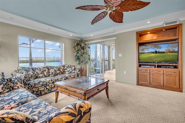 carpeted living room featuring crown molding, a raised ceiling, ceiling fan, and a water view