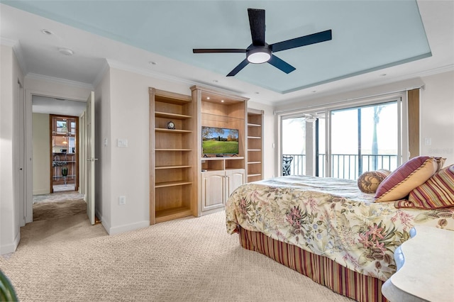 carpeted bedroom with access to exterior, a tray ceiling, ornamental molding, and ceiling fan