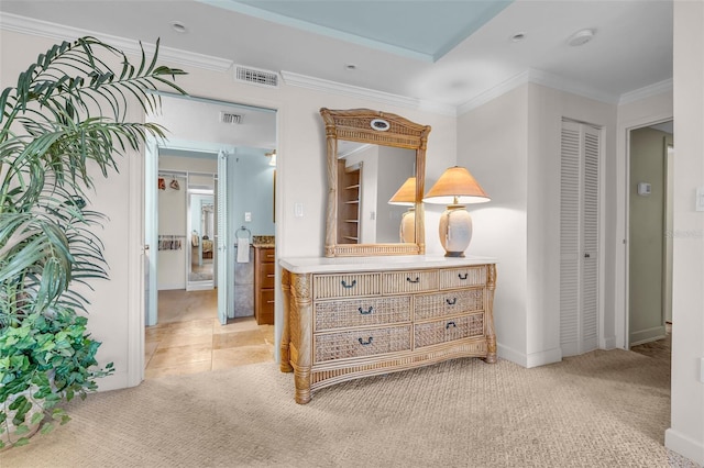 hallway with ornamental molding and light colored carpet