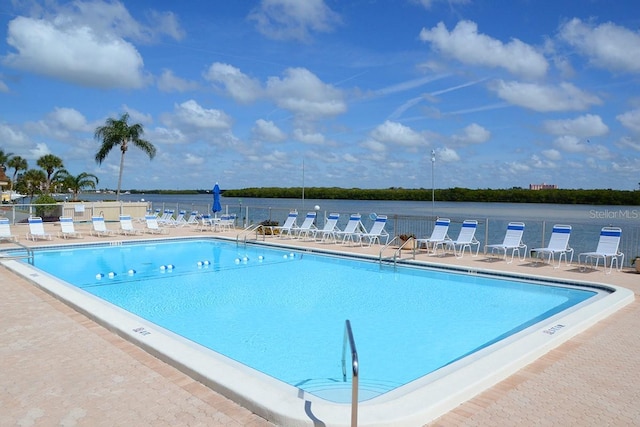 view of pool featuring a water view and a patio