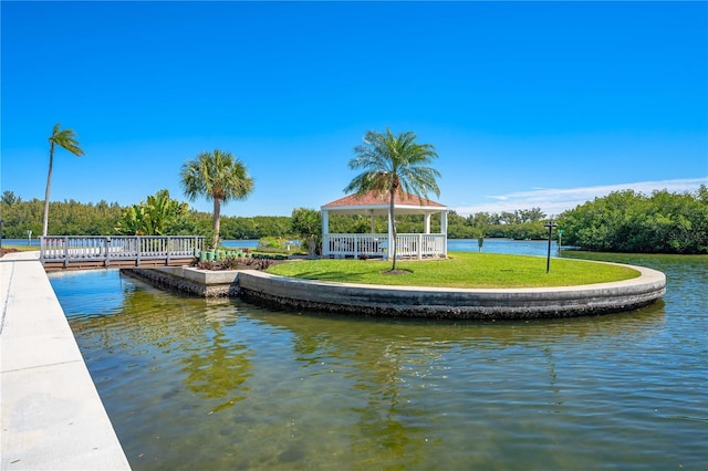 dock area with a gazebo, a water view, and a lawn