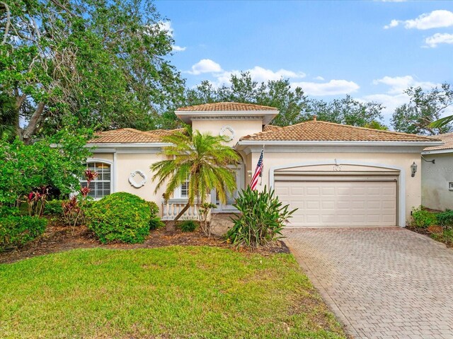 108 Corte Del Rosa, Venice, FL 34285 - mediterranean / spanish home with an attached garage, decorative driveway, stucco siding, a front lawn, and a tile roof
