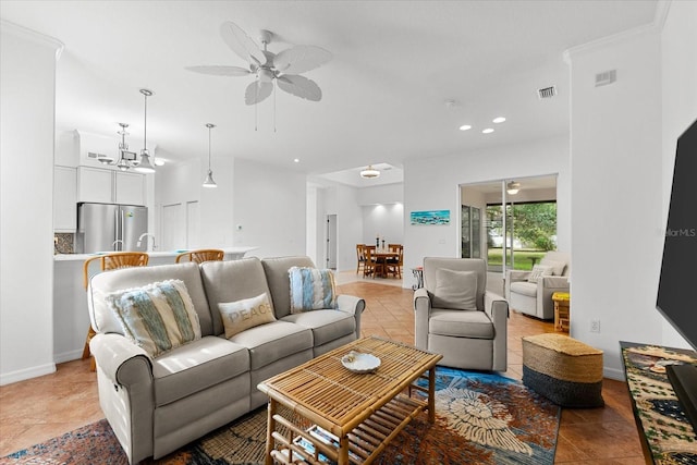 tiled living room with ceiling fan with notable chandelier and crown molding