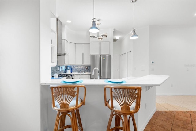 108 Corte Del Rosa, Venice, FL 34285 - kitchen with stainless steel refrigerator, tile patterned floors, light countertops, a breakfast bar area, and a peninsula