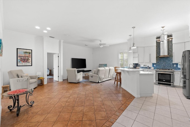 living room featuring light tile patterned floors, ceiling fan with notable chandelier, and sink