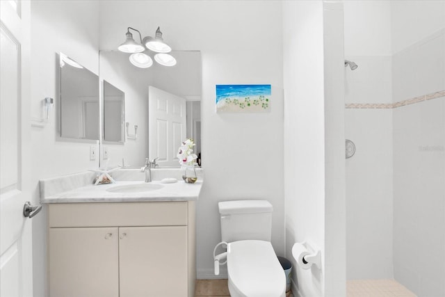 bathroom with tile patterned flooring, vanity, toilet, and tiled shower