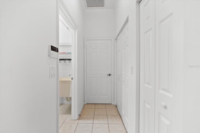 hallway featuring light tile patterned floors and ornamental molding