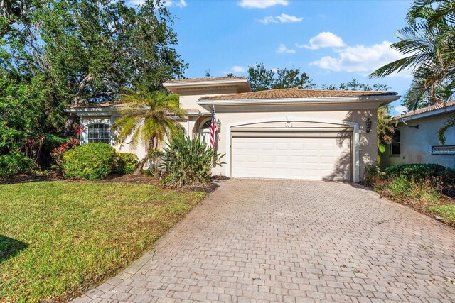 108 Corte Del Rosa, Venice, FL 34285 - mediterranean / spanish house featuring decorative driveway, an attached garage, stucco siding, and a front lawn