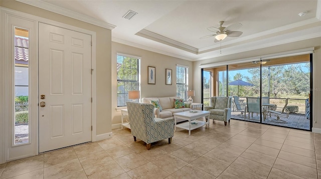 living room with a tray ceiling, ceiling fan, and light tile patterned floors