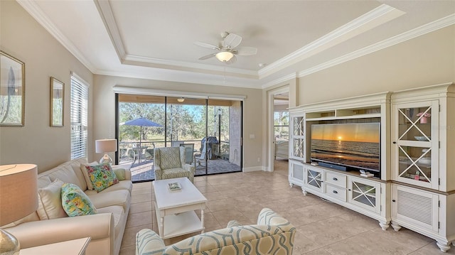 tiled living room with a raised ceiling, ceiling fan, and ornamental molding