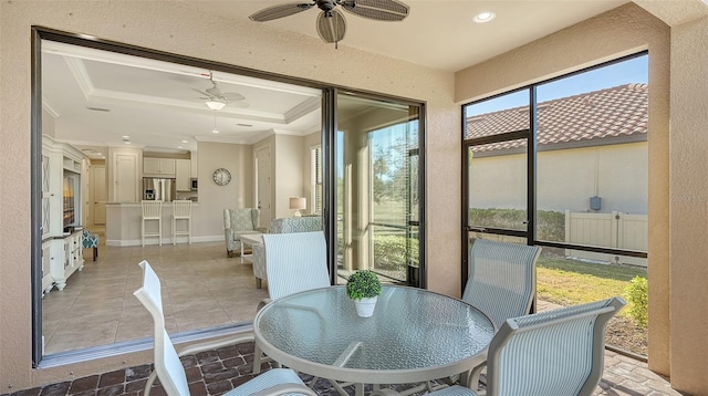 sunroom / solarium featuring a raised ceiling and ceiling fan