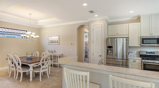 kitchen featuring white cabinetry, light stone countertops, a chandelier, decorative light fixtures, and appliances with stainless steel finishes