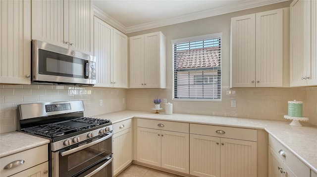 kitchen featuring backsplash, crown molding, cream cabinets, and stainless steel appliances