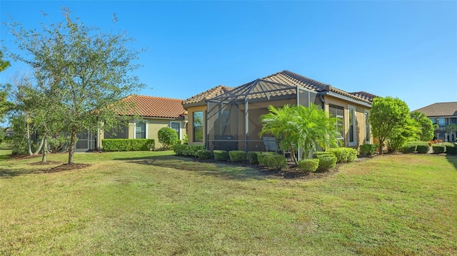 rear view of property featuring a lawn and a lanai