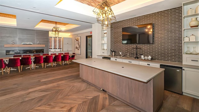 kitchen with a raised ceiling, sink, a center island, stainless steel refrigerator, and hanging light fixtures