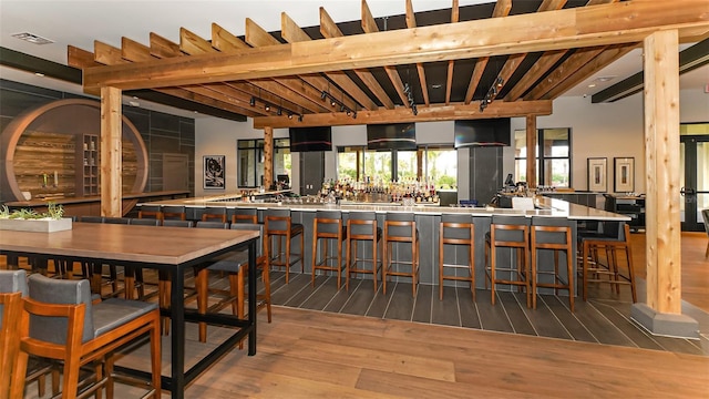 bar featuring beam ceiling and light hardwood / wood-style floors