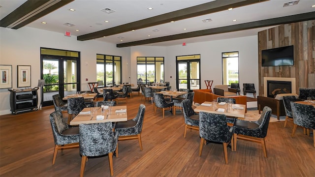 dining space featuring hardwood / wood-style flooring, a healthy amount of sunlight, a fireplace, and french doors