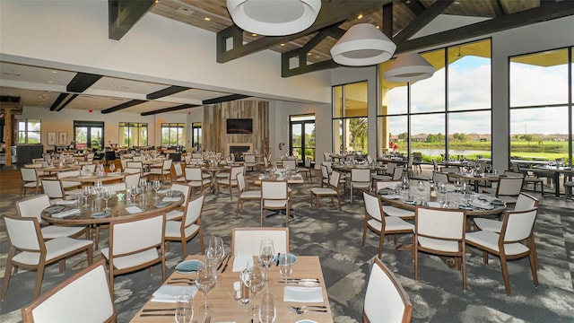 dining area featuring beamed ceiling, a towering ceiling, and a fireplace