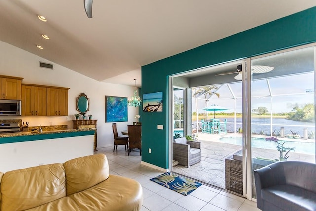 interior space with a water view, sink, light tile patterned floors, and lofted ceiling