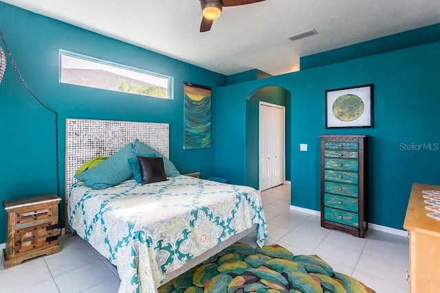 tiled bedroom with ceiling fan and a closet