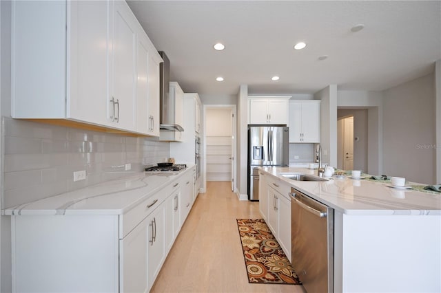 kitchen with tasteful backsplash, stainless steel appliances, sink, light hardwood / wood-style flooring, and white cabinetry